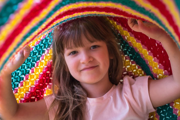 Portrait of lovely toddler girl playing under blanket. Lifetime moments and happy childhood concept.