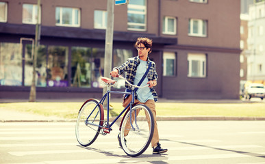 people, style, city life and lifestyle - young hipster man with shoulder bag and fixed gear bike crossing crosswalk on street