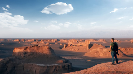 Traveler on the background of rocky formations in the Dasht e Lut desert. Nature of Iran. Persia.