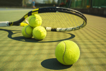 Tennis balls and racket on the grass court. Close-up. Concept of sport, healthy lifestyle.