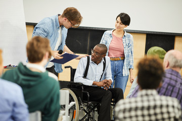 Live interaction with disabled young scientist: content young man in glasses supporting black man...