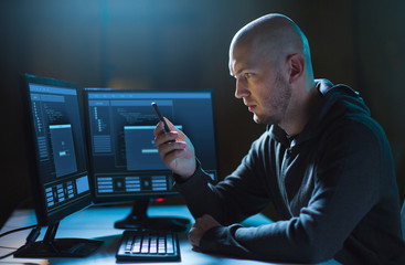cybercrime, hacking and technology concept - male hacker with smartphone and progress loading bar...