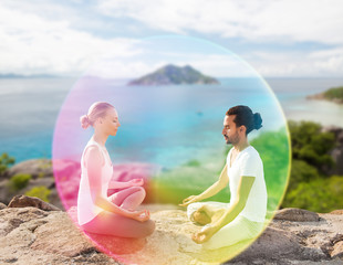 mindfulness, spirituality and outdoor yoga - couple meditating in lotus pose with rainbow aura over...