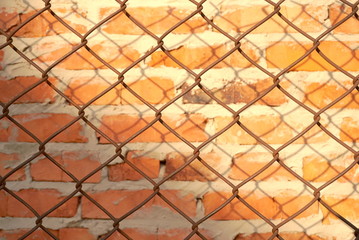 Fototapeta premium Wire fence in front of brick wall