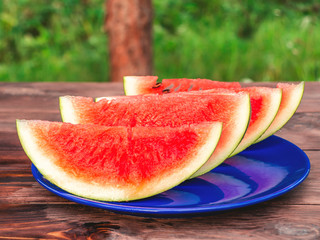 Sliced ripe red watermelon on a blue plate on a wooden table