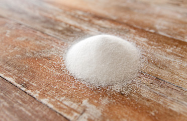 Fototapeta na wymiar food, junk-food, cooking and unhealthy eating concept - close up of white sugar heap on wooden table
