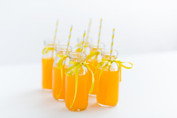 drinks and party concept - close up of orange juice or lemonade in decorated glass bottles with...