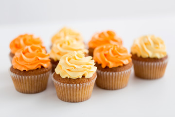 food, pastry and confectionery concept - cupcakes with buttercream frosting over white background
