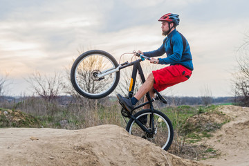Fototapeta na wymiar Man on a mountain bike in red shorts and blue sweater performing a dirt jump. Active lifestyle.