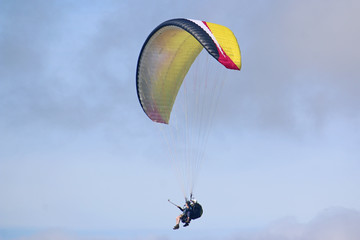 Tandem paraglider flying yellow wing