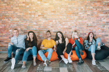 Millennials hanging out in lounge zone. Young people resting in bean bags, having fun together, enjoying break at work. - obrazy, fototapety, plakaty