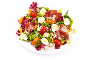 Vegetable salad. Salad of tomatoes, jamon, frisee, rucola and quail eggs, close-up, isolated on white background