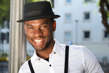 Close up stylish young african american man smiling with suspenders and hat