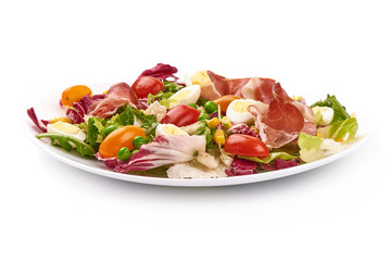 Vegetable salad. Salad of tomatoes, jamon, frisee, rucola and quail eggs, close-up, isolated on white background