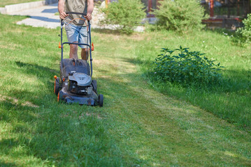 Country works on the personal plot using lawn mower.