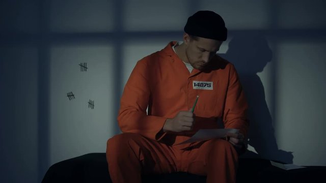 Caucasian male prisoner writing letter, missing family, composing mercy petition