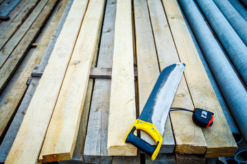 saw with a construction tape measure on wooden boards. Saw. Construction tape. Wooden planks