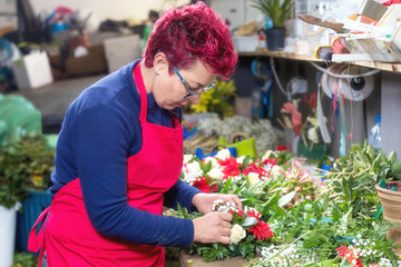 Fototapeta na wymiar Portrait of female florist creating beautiful bouquet at flower shop .