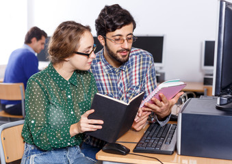 Female and male students working in computer room in library