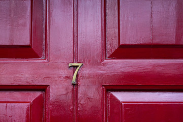 House number seven with the 7 in brass on a burgundy red front door
