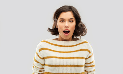 emotion, expression and people concept - surprised young woman in striped pullover over grey background
