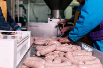 Workers process meat sausages at the meat factory sausage production of fresh meat