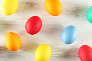 Bunch of blank painted Easter eggs of different pastel color on white wood textured table background with a lot of copy space for text. Top view, flat lay, close up.