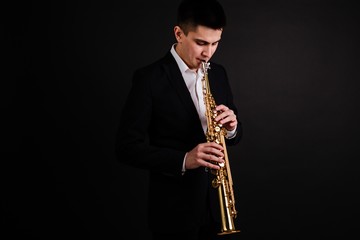Saxophonist in black classic suit playing jazz on soprano saxophone