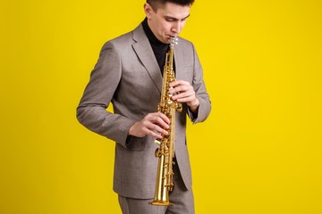 Fototapeta na wymiar Saxophonist plays jazz music on soprano saxophone on yellow