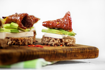 Delicious hearty sandwiches with cheese, avocado and dried tomatoes. Concept for food, healthy food and vegetarians.