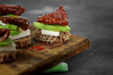 Hearty sandwiches with cheese, avocado and dried tomatoes. Close-up. Concept for food, healthy food and vegetarians.