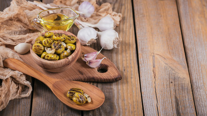 Grilled olives with garlic, olive oil and spices on wooden background