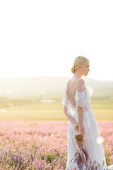 Fototapeta na wymiar Wonderful portrait of girl in light dress in lavender field on sunset