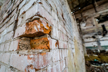 Close-up of old bricks wall in the abandoned place. Ruined and collapsed abandoned building with broken red bricks