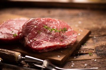 Raw beef steak and spices on wooden cutting board