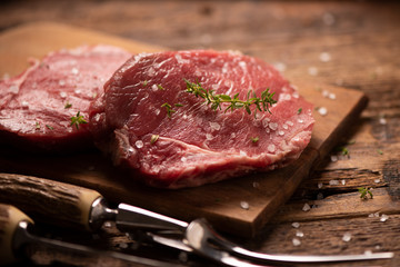 Raw beef steak and spices on wooden cutting board