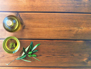 olive oil with a branch of green olives on wooden background