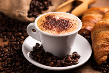 Cup of coffee surrounded by coffee beans