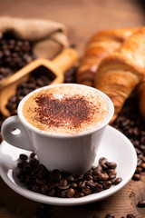 Cup of coffee surrounded by coffee beans