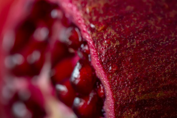 Water drops on a pomegranate peel. A pomegranate. Blurry seeds of fruit. Macro. Healthy concept. Copy space. Image soft focus or doesn’t in focus.