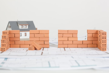 Model house construction with brick on blueprint