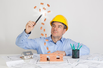 Architect using magic pen and building model house construction with brick.