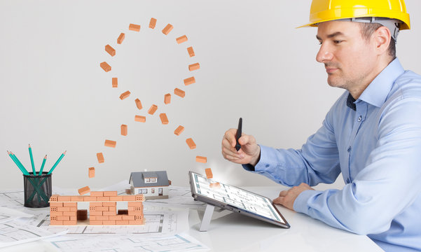 Architect using magic digital tablet and building model house construction with brick.