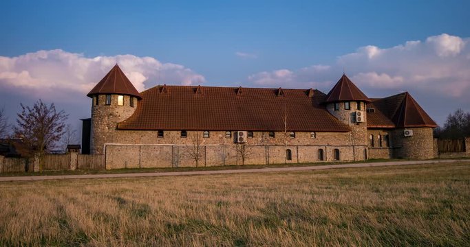 Timelapse video of modern castle tower and sky with moving clouds in sunset