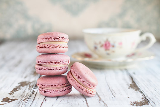 Stack of fresh French pink strawberry macarons on a white rustic table.