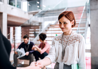 Group of young businesspeople standing on a staircase, shaking hands.