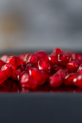 Pomegranate seeds. Gray background and red grains granate. Macro. Copy space. Toned image of soft focus or doesn’t in focus.