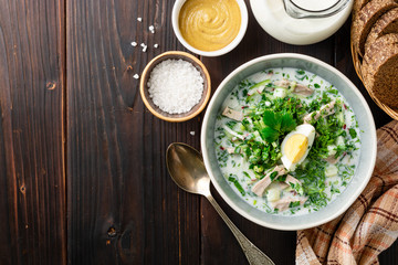 Traditional Russian summer cold soup okroshka with kefir in bowl on dark wooden background. Top view. Copy space.