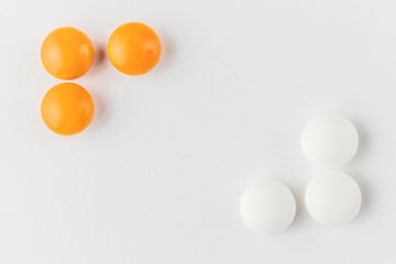 White and orange tablets on a light background close-up. Minimalistic image suitable as a background on the theme of medicine and health.