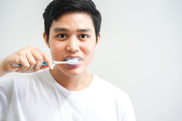 close up young asian man brushing teeth at bathroom in the morning , lifestyle daily concept